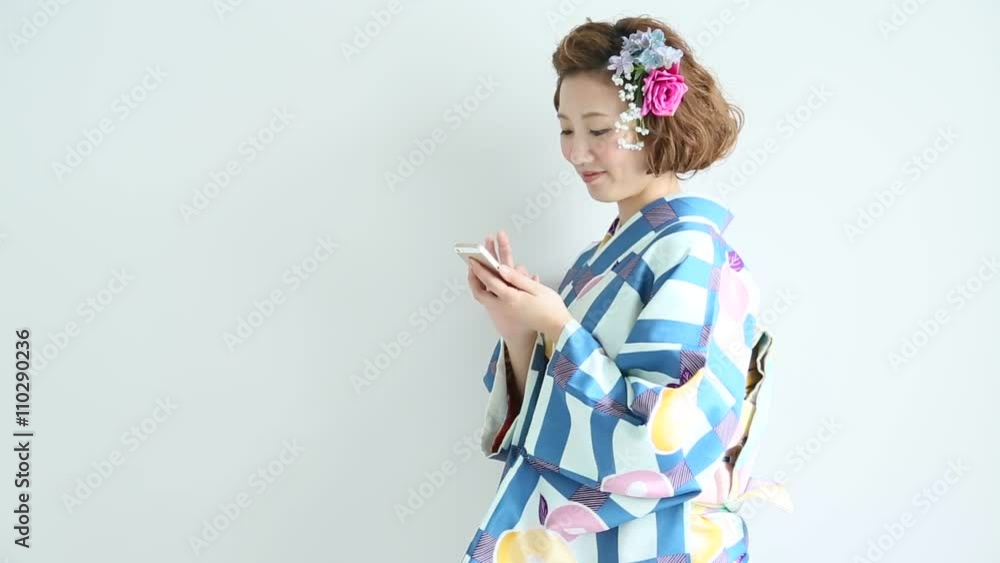 着物でスマートフォンを操作する女性 着物でスマートフォンを操作する女性