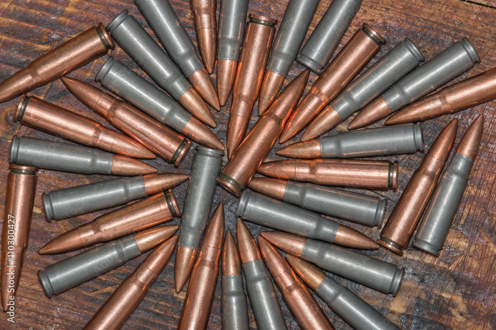Bullets of 7.62 mm caliber. Kalashnikov machine gun on the wooden background. Bullets of 7.62 mm caliber. Kalashnikov machine gun on the wooden background.