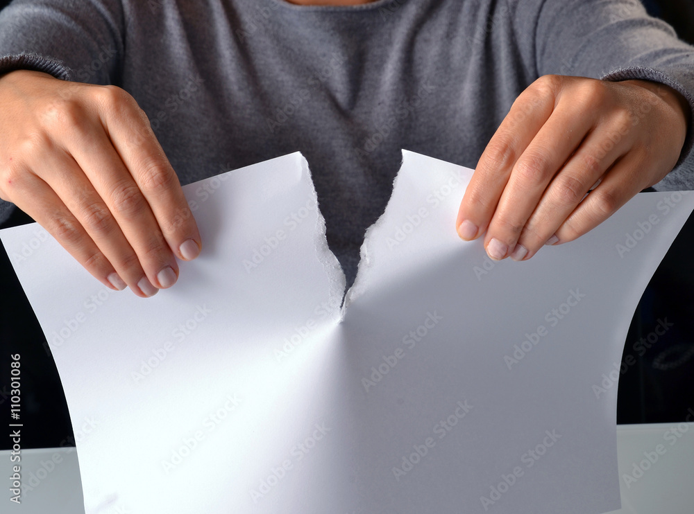 Mano rompiendo por la mitad un documento, una hoja blanca. Stock Photo