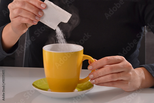 Agregando sobre de azúcar a la taza de cafe. photo