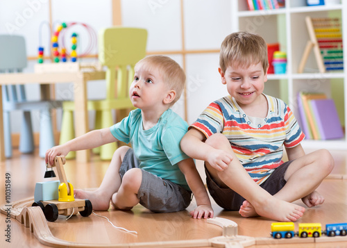 children  playing rail road toy in playroom
