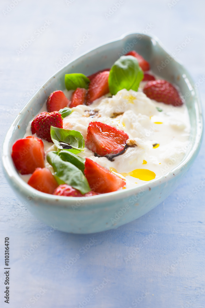 Creamy stracciatella with strawberries, basil, olive oil and balsamic vinegar. Selective focus. Creamy stracciatella with strawberries, basil, olive oil and balsamic vinegar. Selective focus.