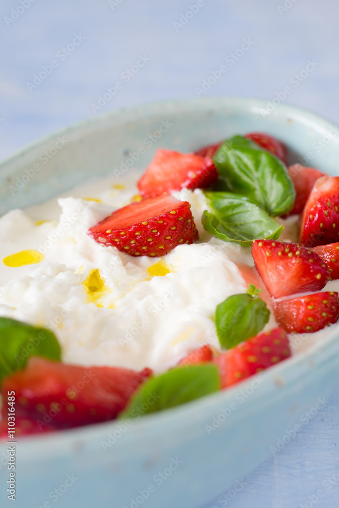 Creamy stracciatella with strawberries, basil and olive oil. Selective focus. Creamy stracciatella with strawberries, basil and olive oil. Selective focus.