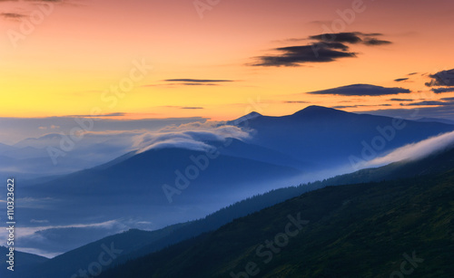 Sunrise landscape of foggy and cloudy mountain valley.
