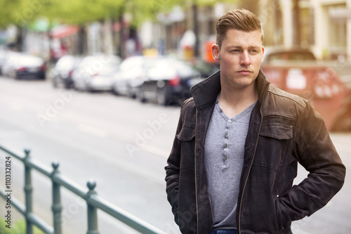 young blond man standing outside on the street