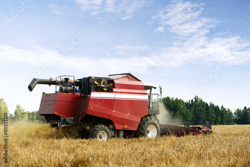 red harvesting combine working on a wheat field