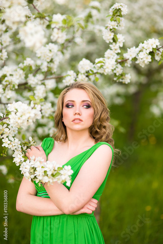 Beautiful happy young woman in spring blossoming garden