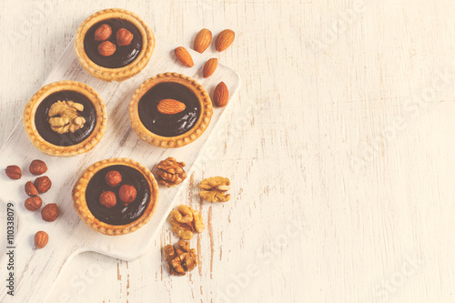 Almond walnut hazelnut chocolate small tarts on a white backgrou © colnihko