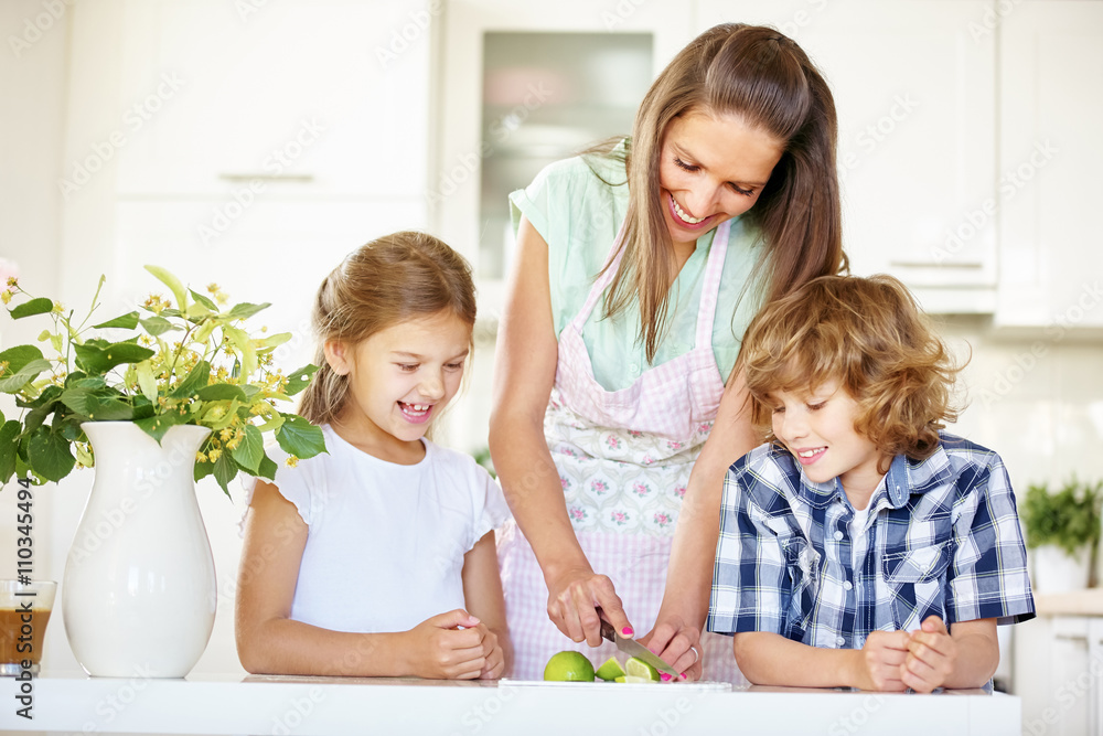 Mutter und Kinder schneiden Limette in Küche Mutter und Kinder schneiden Limette in Küche