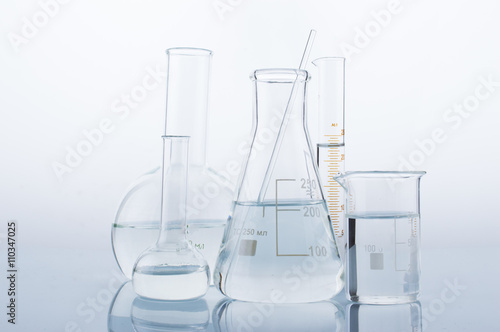 Different laboratory glassware with water and empty with reflection on white background