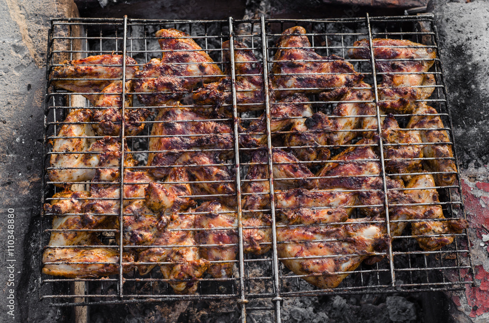 Closeup Grilled chicken wings barbecue on grid over charcoal. Selective focus