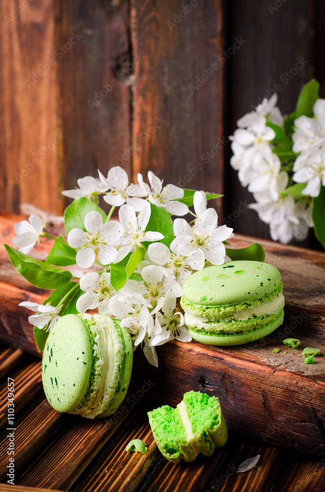 Green color Macaroons with spring flowers on wooden vintage background. Selective focus Green color Macaroons with spring flowers on wooden vintage background. Selective focus