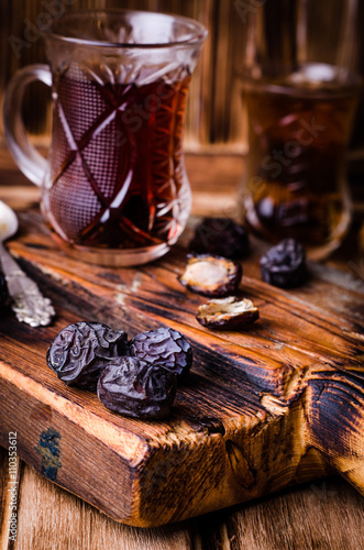 Dates with tea cup on vintage wooden background. Selective focus. Toned image