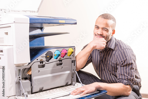 smiling technician sitting near copier