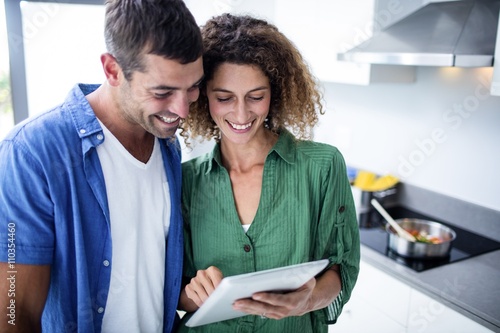 Happy couple using digital tablet in kitchen