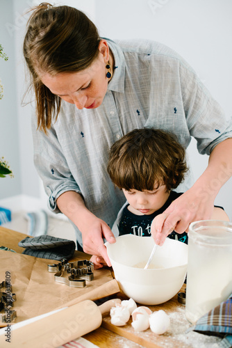 Little boy helping his mother with the baking in the kitchen sta photo
