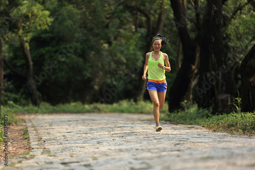 young woman trail runner running in forest