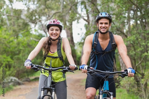 Cheerful young couple with mountain bikes on footpath