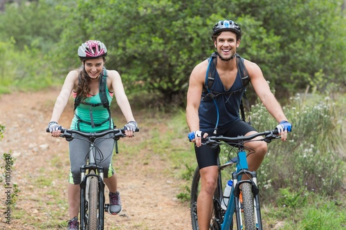 Portrait of couple riding bicycles on dirt road