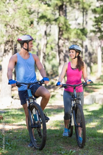 Young couple riding bicycle at forest