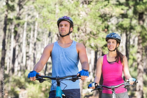 Young couple riding bicycle at forest