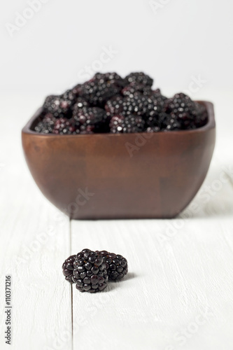 two blackberry fruit in front of bowl full of blackberries