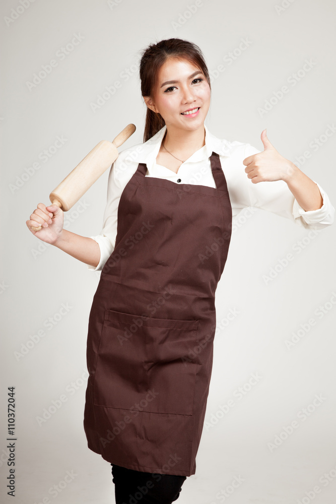 Asian Baker woman in apron thumbs up with wooden rolling pin Asian Baker woman in apron thumbs up with wooden rolling pin