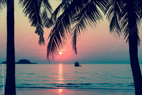 Beautiful bloody sunset on a tropical beach, palm trees silhouettes.
