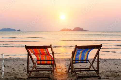 Two lounge chairs on sunset beach.