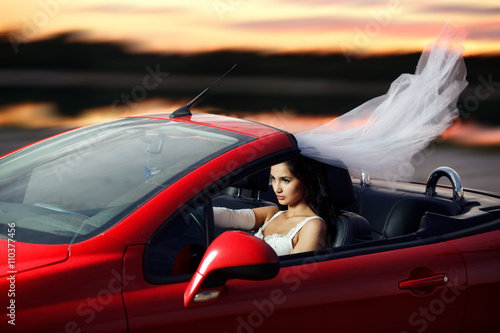 Obraz na plátně Sexual bride riding in a red sports car