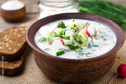 Okroshka on kefir with rye bread on a wooden table