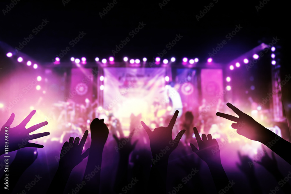 Audience with hands raised at a music festival and lights streaming down from above the stage. live concert, music festival, happy youth, luxury party, landscape exterior.