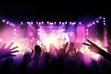 Audience with hands raised at a music festival and lights streaming down from above the stage. live concert, music festival, happy youth, luxury party, landscape exterior.