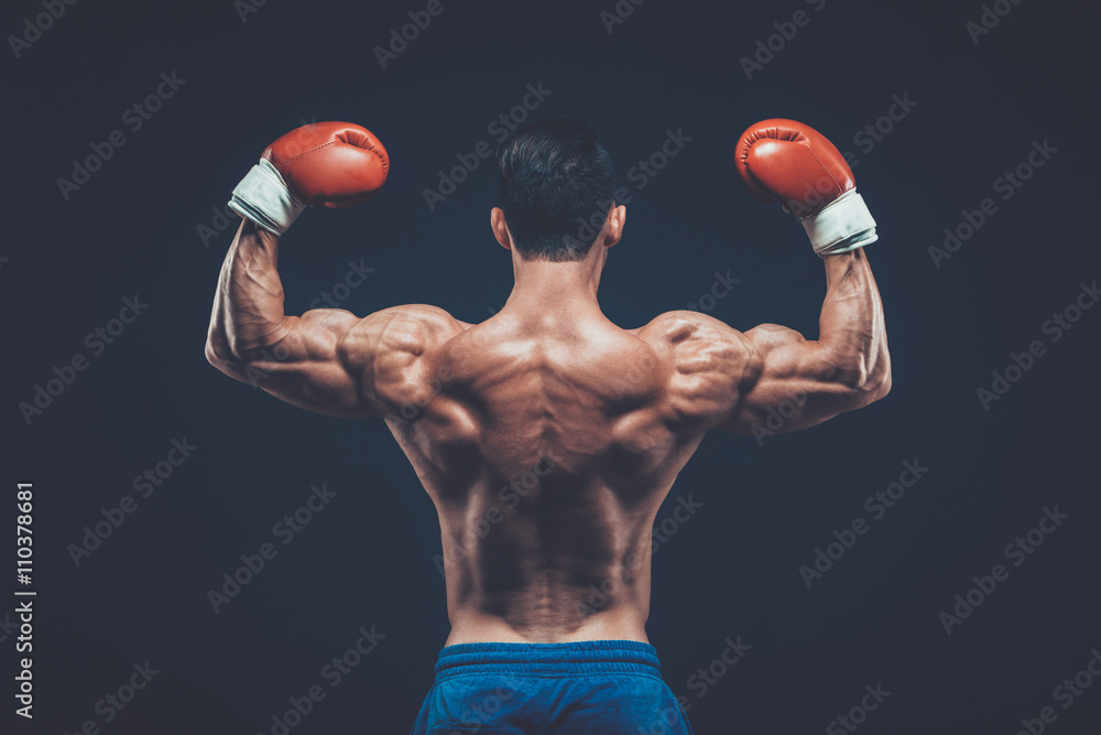 Muscular boxer in studio shooting, on black background.