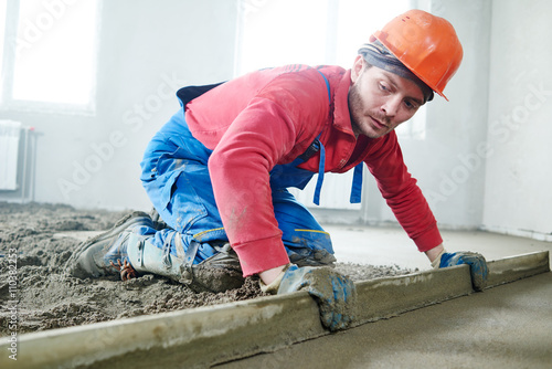 worker screeding indoor cement floor with screed  photo