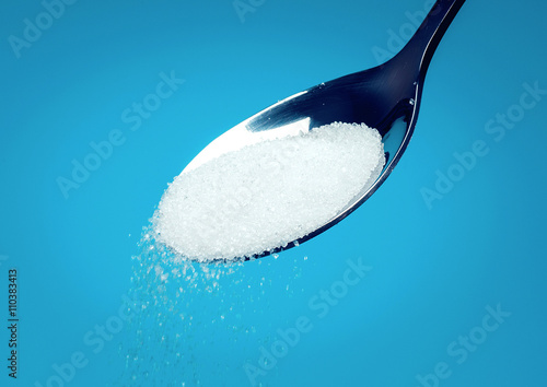white Sugar spoon blue background.