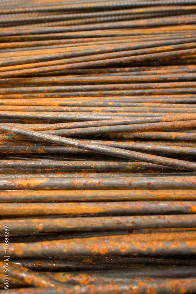Low angle vertical MCU perspective of thin semi-rusty steel bars stacked in a horizontal position