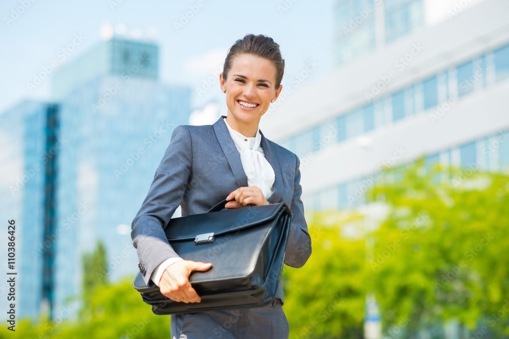 Smiling business woman in office district holding briefcase Smiling business woman in office district holding briefcase