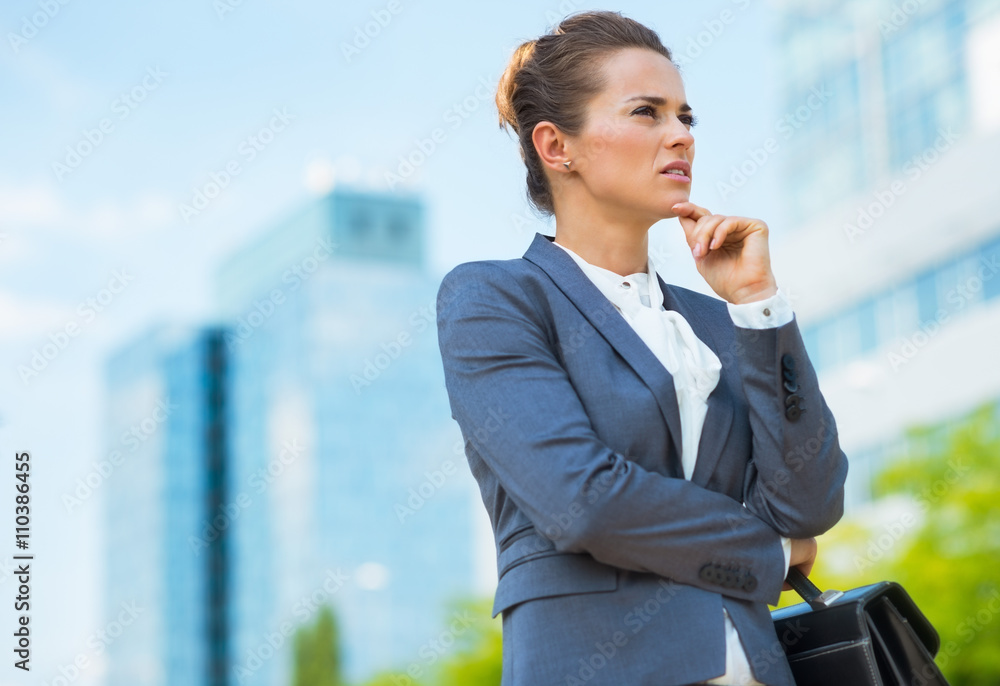 Fototapeta premium Pensive business woman with briefcase in office district