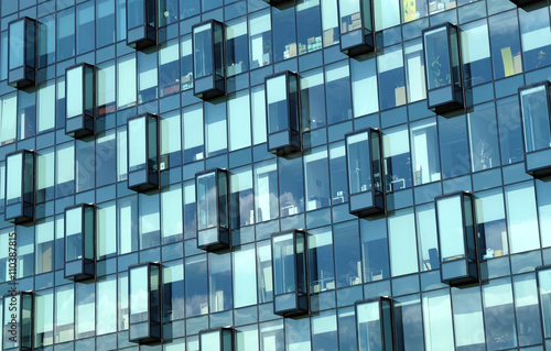 Facade with glass wall of modern office building with many large panoramic windows in business cluster front view close-up