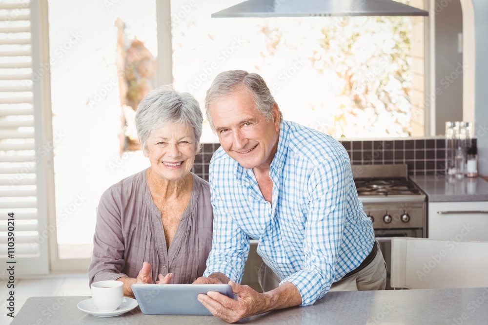 Portrait of happy senior couple with tablet