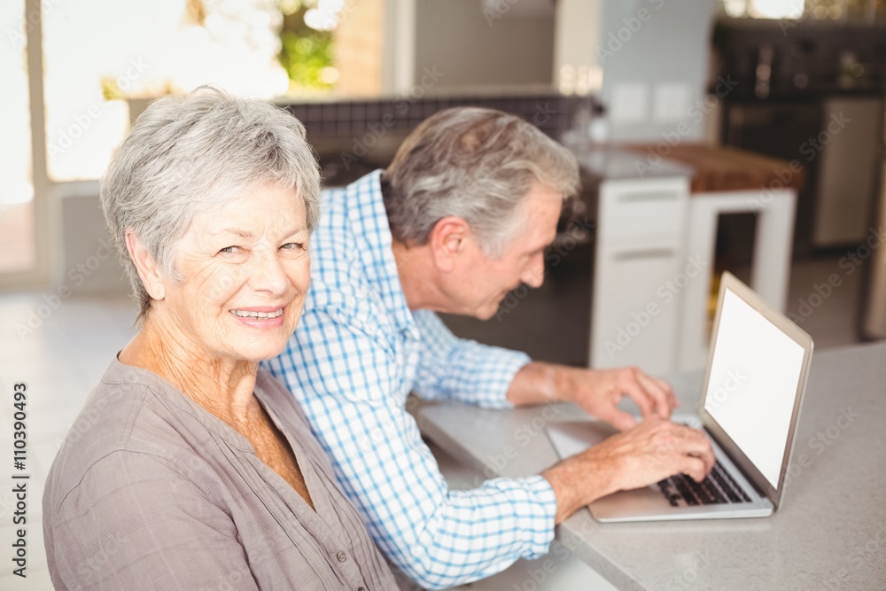 Portrait of senior woman with husband using laptop in background Portrait of senior woman with husband using laptop in background