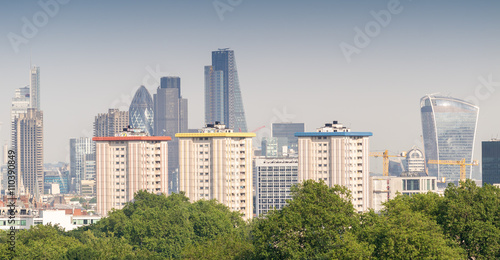City of London skyline over green trees