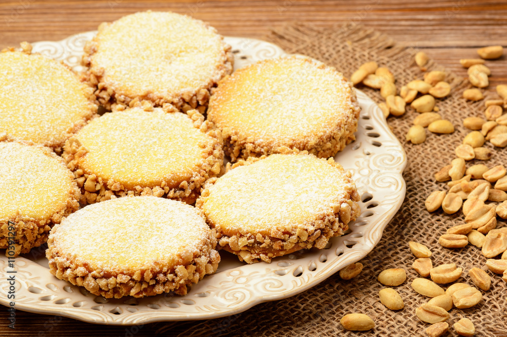 Butter cookies (alfajores) with caramel and peanut on wooden background.