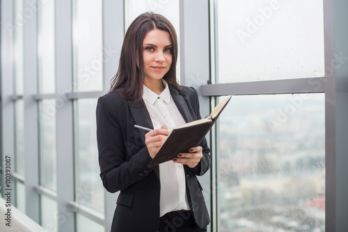Business woman with notebook is window in office