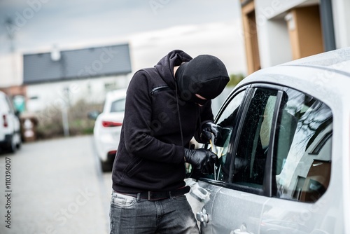 Murais de parede Car thief trying to break into a car with a screwdriver