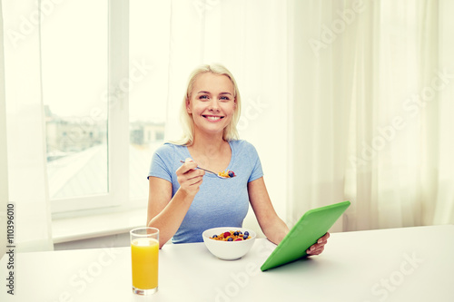woman with tablet pc eating breakfast at home