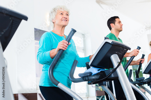 Senior woman on elliptical trainer exercising in gym