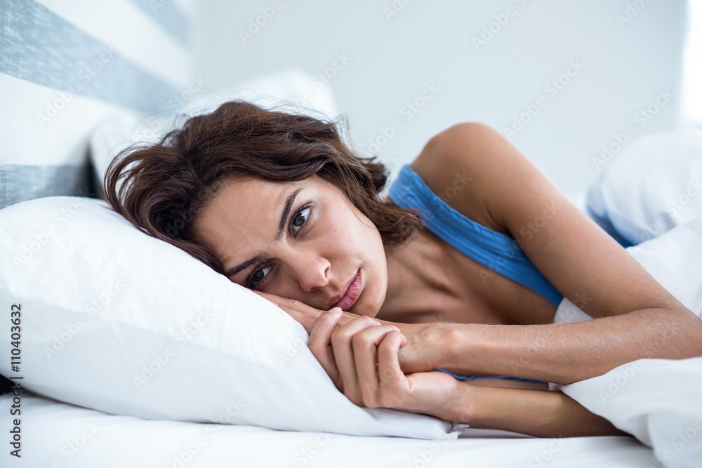 Fototapeta premium Sad woman lying on bed 