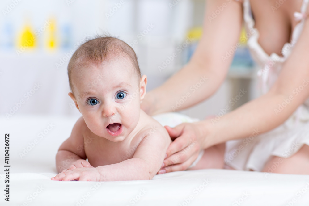 Mother massaging baby in bed at home Mother massaging baby in bed at home